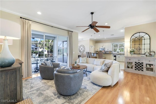 living room with crown molding, ceiling fan, and light hardwood / wood-style floors