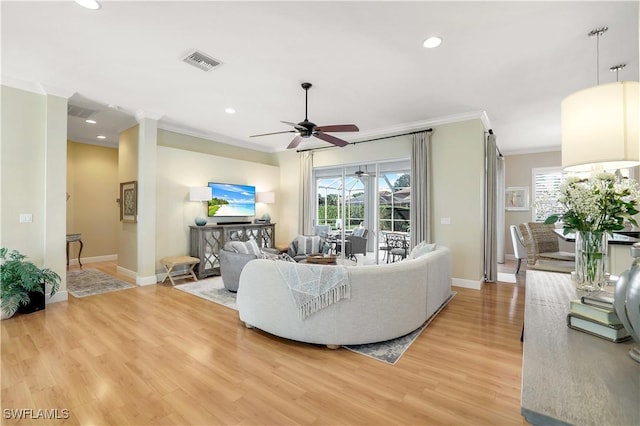 living room with ornamental molding, a ceiling fan, visible vents, light wood finished floors, and baseboards