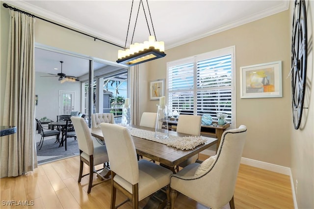 dining area featuring light wood-type flooring, crown molding, baseboards, and ceiling fan with notable chandelier