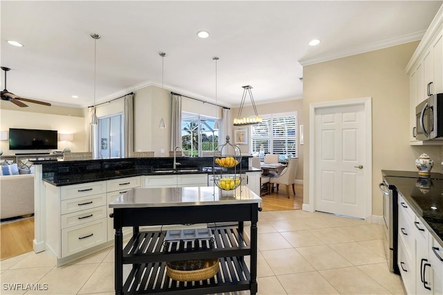 kitchen featuring light tile patterned floors, ornamental molding, open floor plan, stainless steel appliances, and a sink