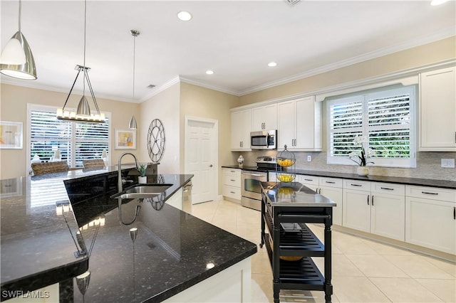 kitchen with sink, dark stone counters, decorative light fixtures, white cabinets, and appliances with stainless steel finishes