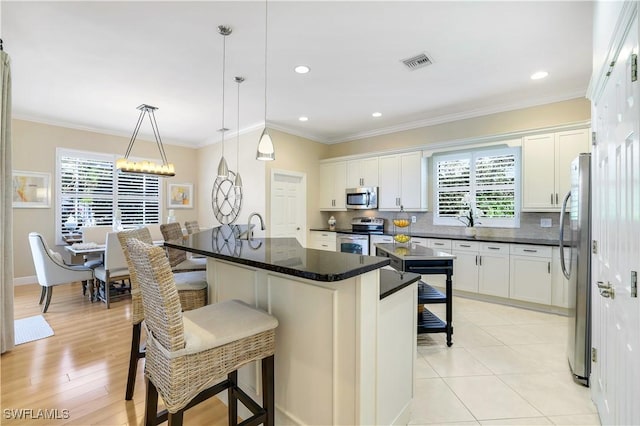 kitchen featuring plenty of natural light, visible vents, decorative backsplash, stainless steel appliances, and a kitchen bar