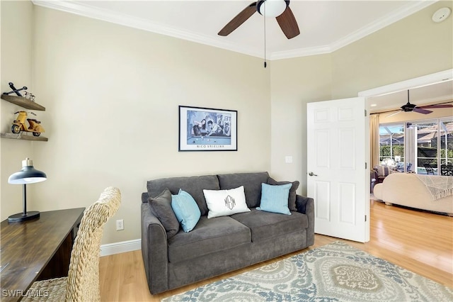 living room featuring ornamental molding, baseboards, a ceiling fan, and light wood-style floors