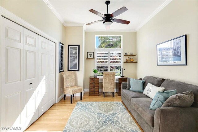 living area featuring baseboards, light wood-style floors, a ceiling fan, and crown molding