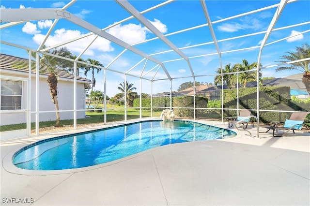 outdoor pool featuring glass enclosure and a patio area