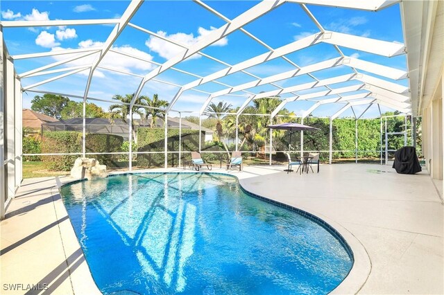 view of pool featuring glass enclosure and a patio area