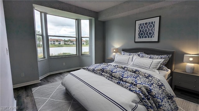 bedroom featuring a water view and dark hardwood / wood-style floors