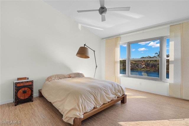 bedroom featuring ceiling fan and a water view