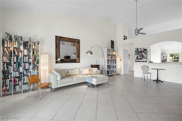 tiled living room with ceiling fan and high vaulted ceiling