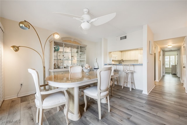 dining room with ceiling fan, light hardwood / wood-style flooring, and sink