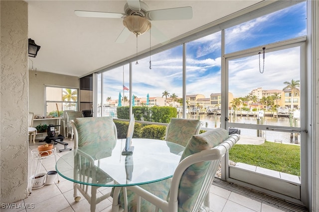 sunroom / solarium featuring ceiling fan and a water view