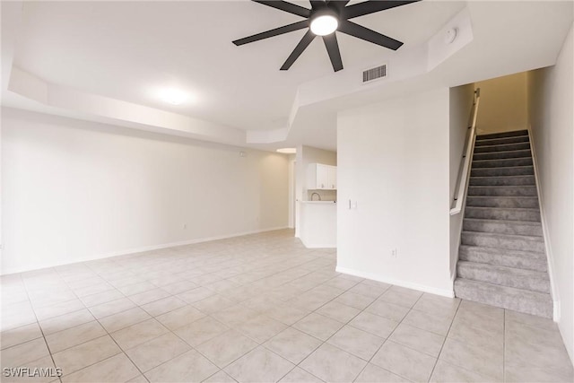 interior space featuring light tile patterned floors, a tray ceiling, and ceiling fan