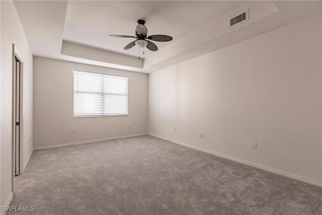 carpeted empty room featuring ceiling fan and a tray ceiling