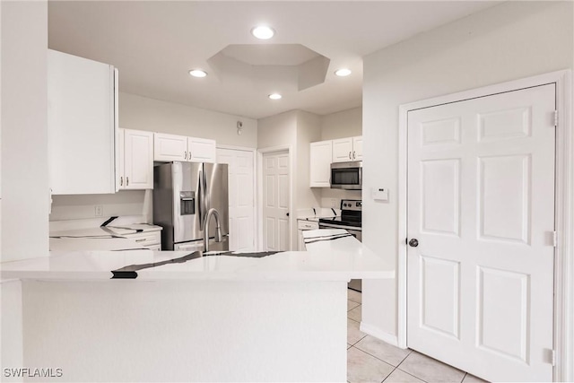 kitchen featuring white cabinets, sink, light tile patterned floors, appliances with stainless steel finishes, and kitchen peninsula