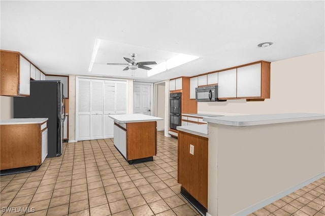 kitchen with black appliances, ceiling fan, a center island, and a skylight