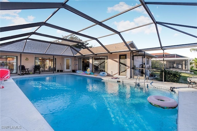 view of pool with glass enclosure and a patio