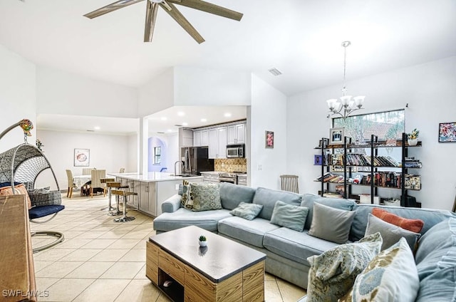 tiled living room featuring ceiling fan with notable chandelier and sink