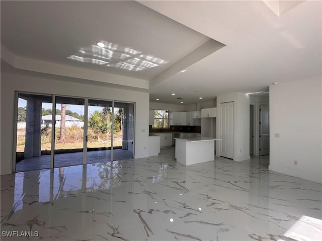 unfurnished living room with a raised ceiling and sink