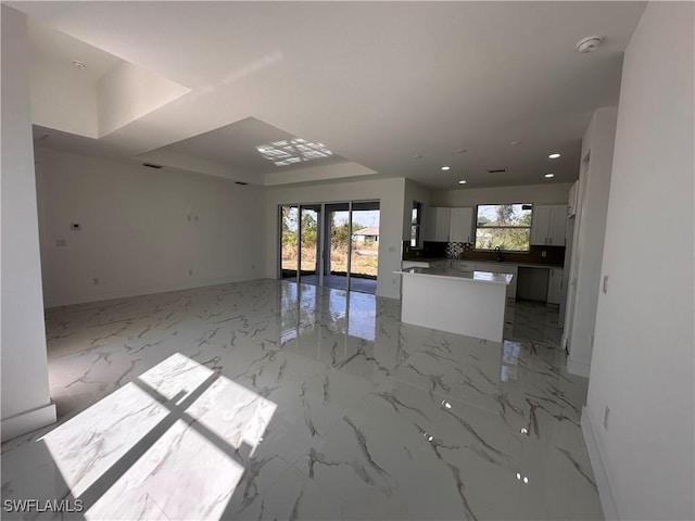 unfurnished living room featuring a raised ceiling and sink