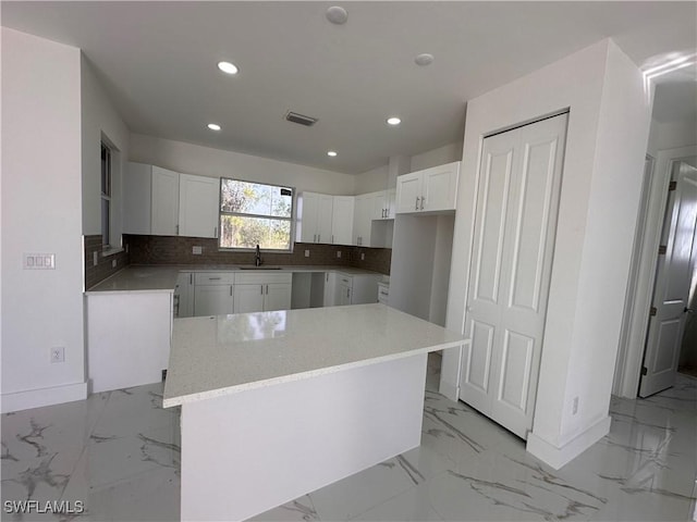 kitchen featuring white cabinetry, tasteful backsplash, sink, and a kitchen island