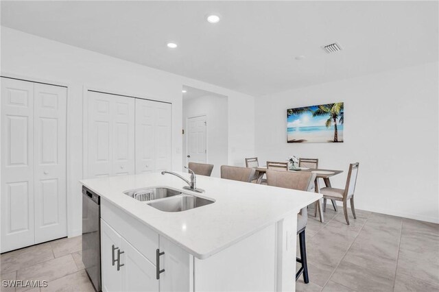 kitchen with dishwasher, sink, an island with sink, a breakfast bar, and white cabinets