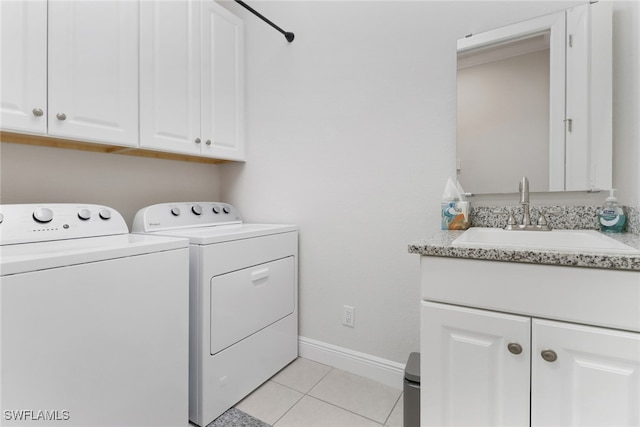 laundry area with sink, washing machine and clothes dryer, light tile patterned floors, and cabinets