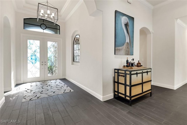 entrance foyer featuring ornamental molding, a chandelier, and french doors