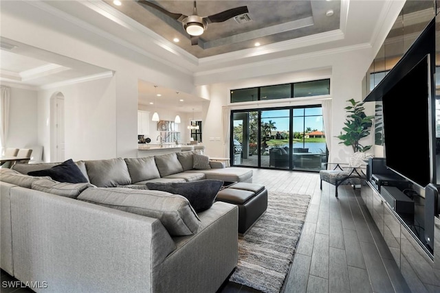 living room with ornamental molding, dark hardwood / wood-style flooring, ceiling fan, and a raised ceiling