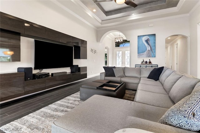 living room featuring crown molding, french doors, ceiling fan with notable chandelier, and a raised ceiling