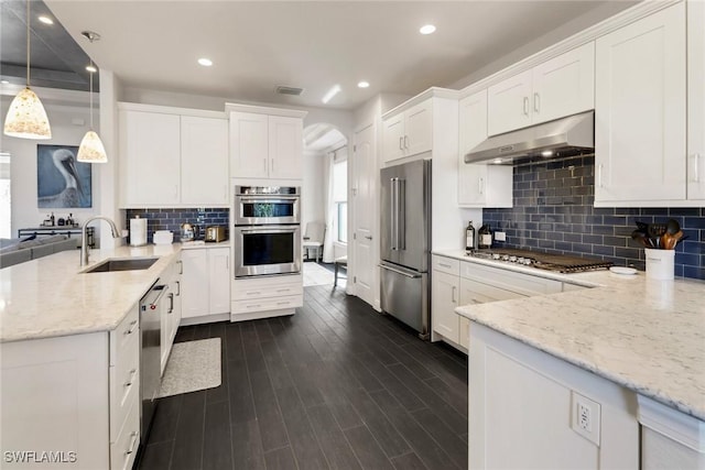 kitchen featuring sink, stainless steel appliances, white cabinetry, and hanging light fixtures