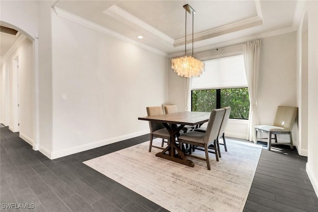 dining area with a notable chandelier, crown molding, dark wood-type flooring, and a tray ceiling