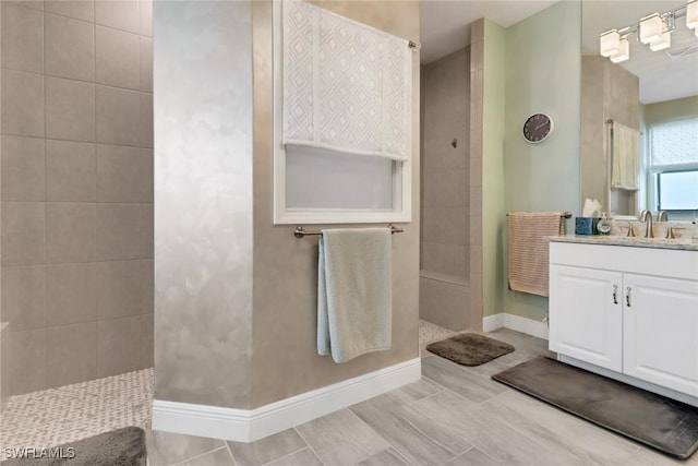 bathroom with tiled shower and vanity