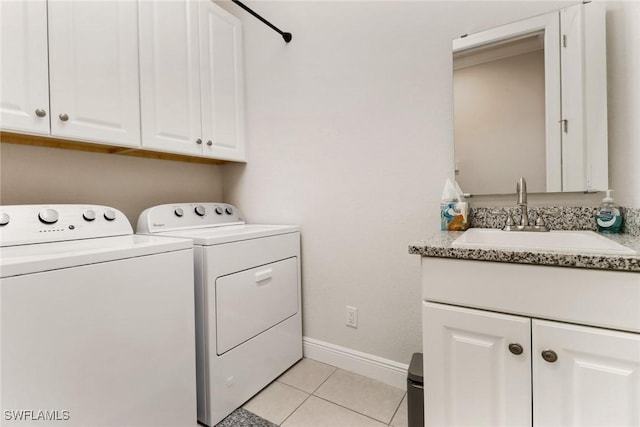 laundry room with sink, washer and clothes dryer, light tile patterned floors, and cabinets