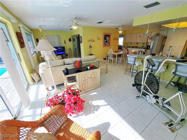 living area with a ceiling fan, visible vents, and light tile patterned floors