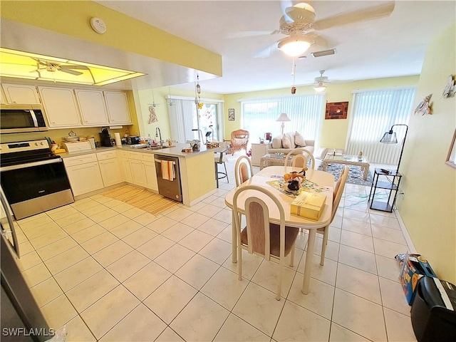 kitchen with stainless steel appliances, a sink, a peninsula, and light tile patterned floors