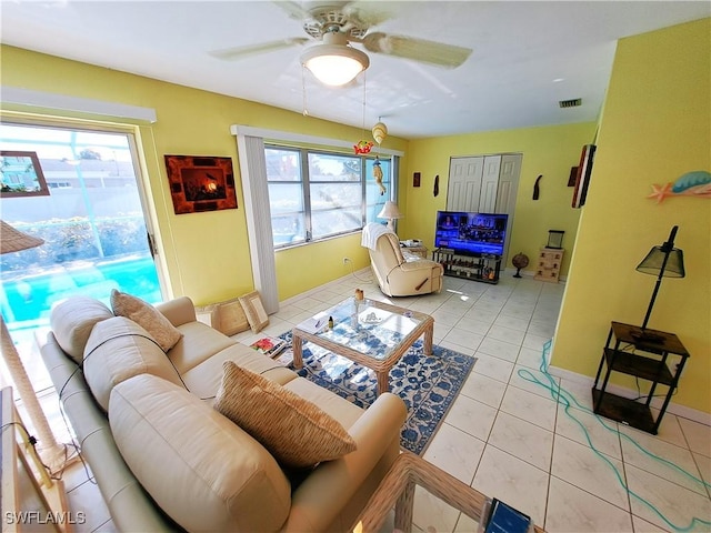 living area with a healthy amount of sunlight, light tile patterned floors, visible vents, and a ceiling fan