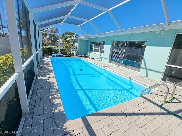 outdoor pool featuring glass enclosure and a patio area