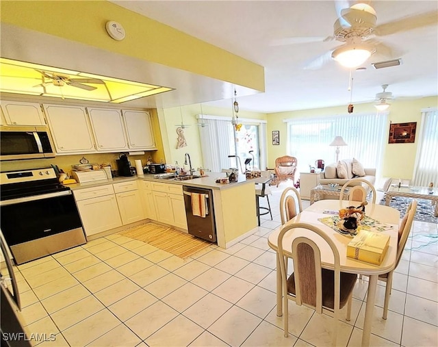 1727 Lakeview Blvd, North Fort Myers, FL 33903 - kitchen with appliances with stainless steel finishes, a sink, a peninsula, a ceiling fan, and light tile patterned flooring