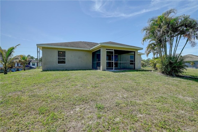 back of house featuring a lawn and a sunroom