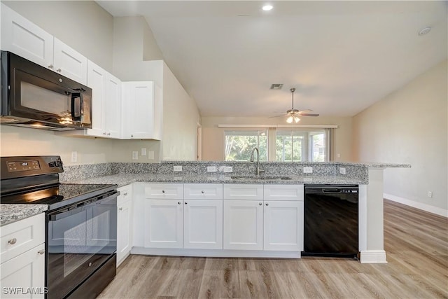 kitchen featuring kitchen peninsula, light stone counters, sink, black appliances, and white cabinets