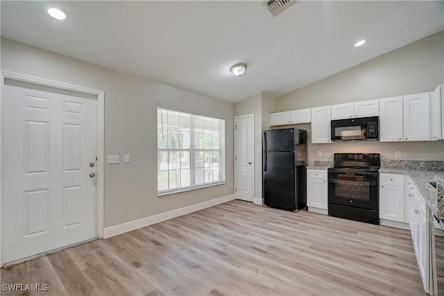 kitchen with light stone countertops, vaulted ceiling, black appliances, light hardwood / wood-style flooring, and white cabinets