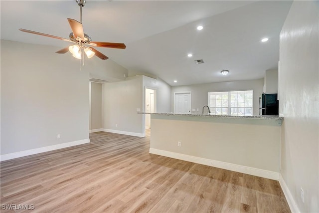 interior space with ceiling fan, lofted ceiling, sink, and light hardwood / wood-style flooring