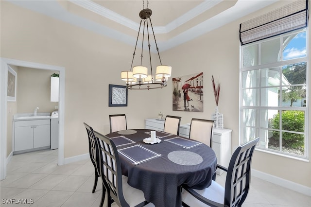 dining space featuring light tile patterned flooring, washer / dryer, sink, a tray ceiling, and crown molding