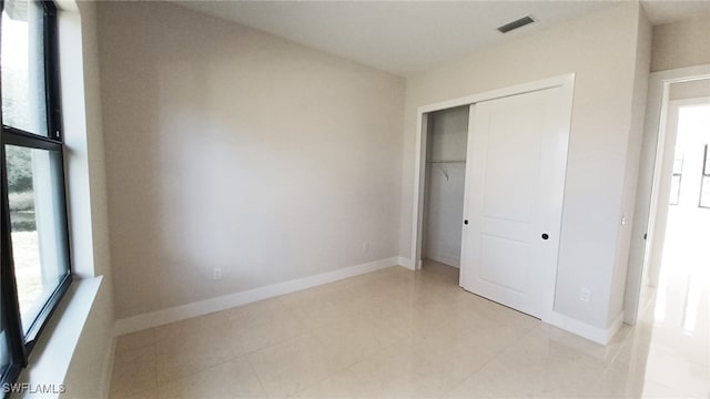 unfurnished bedroom featuring baseboards, visible vents, and a closet