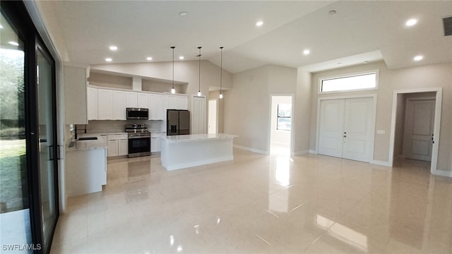 kitchen with sink, stainless steel appliances, white cabinets, a kitchen island, and decorative light fixtures