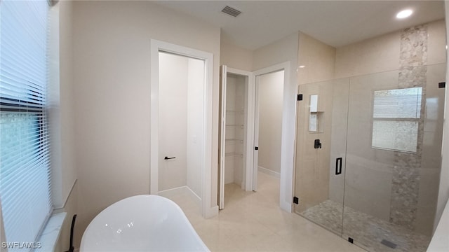 full bathroom featuring visible vents, a shower stall, a freestanding bath, and a walk in closet