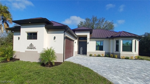 view of front of property featuring a front lawn, stucco siding, metal roof, an attached garage, and a standing seam roof