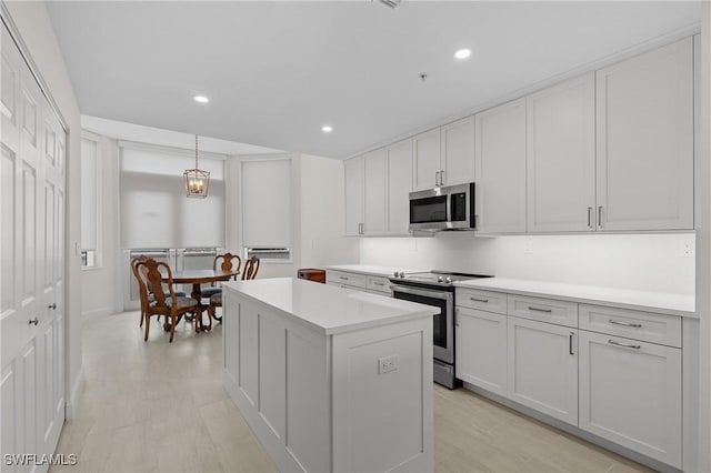 kitchen featuring white cabinetry, a center island, hanging light fixtures, and appliances with stainless steel finishes