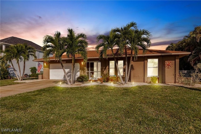 ranch-style home featuring a lawn and a garage