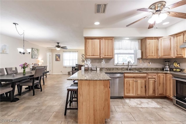 kitchen featuring a breakfast bar, hanging light fixtures, sink, appliances with stainless steel finishes, and a chandelier